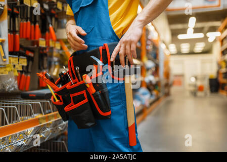 Male builder trying on tool belt in hardware store Stock Photo