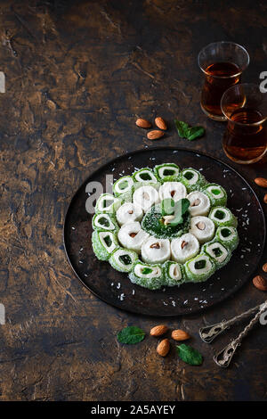 Turkish Delight. Assorted multi-colored oriental sweets with almonds on a round tray on a dark background. Stock Photo
