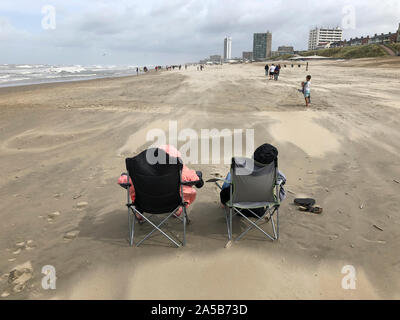 Zandvoort, Netherlands - 14 Aug 2019: Wrapped up in warm blankets, two tourists brave the stormy weather at the beach of Zandvoort, Netherlands. Stock Photo