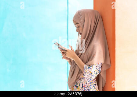 Young Adult Asian Thai Muslim university college student stand and using smart mobile phone. Unising for online education and technology concept Stock Photo