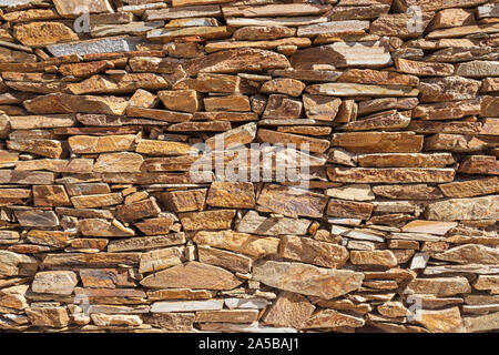 wall of yellow colored slate stones that are expertly stacked without cement Stock Photo