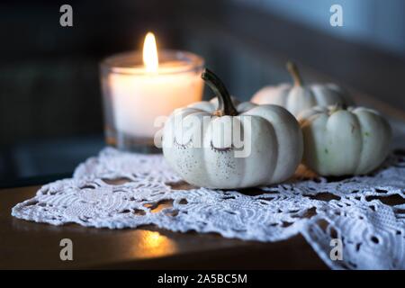 autumn and winter cozy table decoration with candle, small apples and white baby boo pumpkins Stock Photo