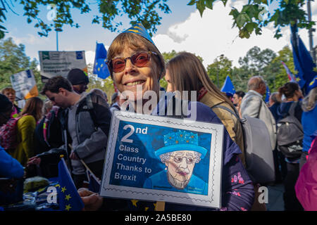 London, UK. 19th October 2019. A woman holds a placard of a stamp  with message 2nd Class Country Thanks to Brexit. A huge crowd meets at Park Lane for the People's Choice march calling for a referendum on the Brexit deal negotiated by Boris Johnson. They say that now we know more about what Brexit would mean the public must be asked to make an informed choice on whether to leave Europe. Many made clear their desire to stay in EU which they say is a far better deal than Johnson has negotiated and that they did not trust the Tories not to pursue a 'no deal' exit if allowed to go ahead. Peter Ma Stock Photo
