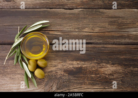 olive oil and olive branch backlit on old wooden background Stock Photo