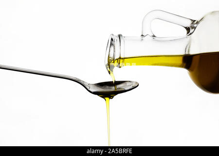 pouring olive oil from glass bottle on white background Stock Photo