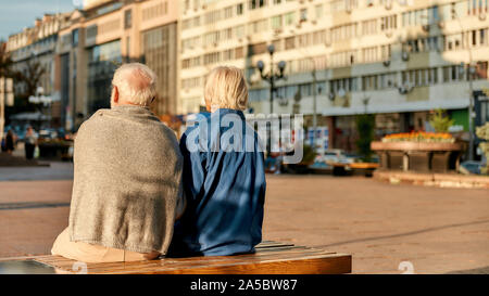 Resting. Back view of senior couple in casual clothes sitting on the bench together Stock Photo