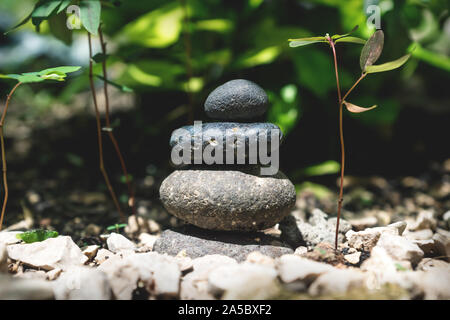 Zen balanced stone tower in a natural garden with green plants in the background Stock Photo