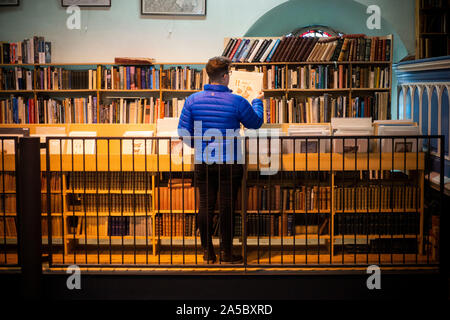 A tourist browses shelves at Leakey's Bookshop, featuring a vast collection of second-hand books, sprawling over two floors in Inverness, Scotland Stock Photo