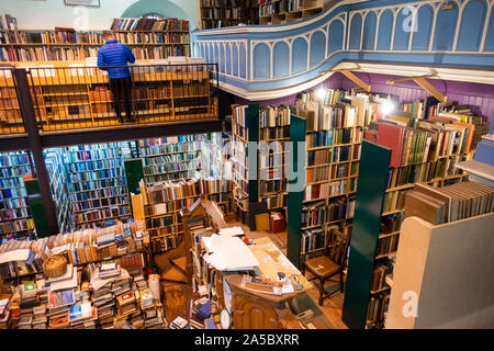 A tourist browses shelves at Leakey's Bookshop, featuring a vast collection of second-hand books, sprawling over two floors in Inverness, Scotland Stock Photo