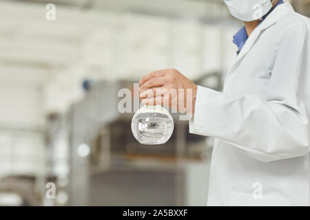 The flask with the water test in the hands of the technologist on the factory. Stock Photo
