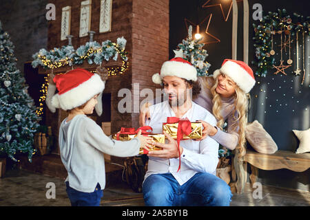 Smiling woman and boy giving presents to man Stock Photo