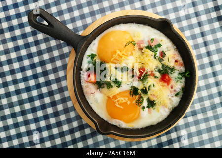 Fried eggs with onion and cheese in a frying pan. Freshly made, delicious meal of eggs and vegetables. Stock Photo