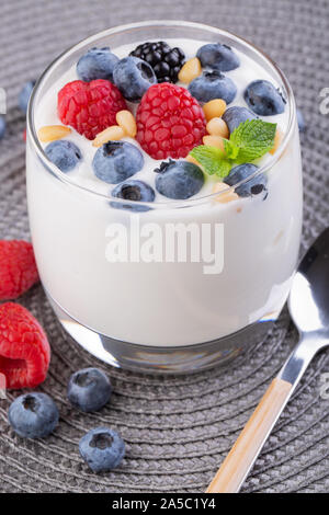 A glass of granola in yogurt with a mix of wild berries on a gray table. Top view, macro shot Stock Photo