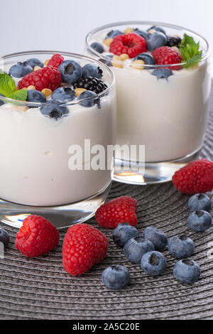 A glass of granola in yogurt with a mix of wild berries on a gray table. Top view, macro shot Stock Photo