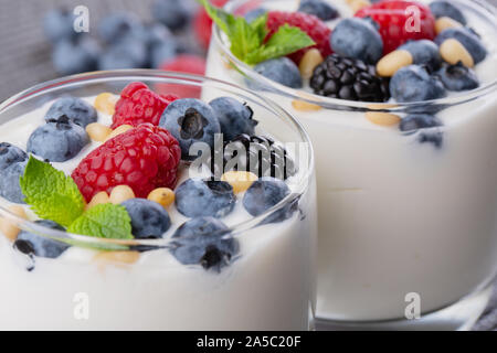 A glass of granola in yogurt with a mix of wild berries on a gray table. Top view, macro shot Stock Photo