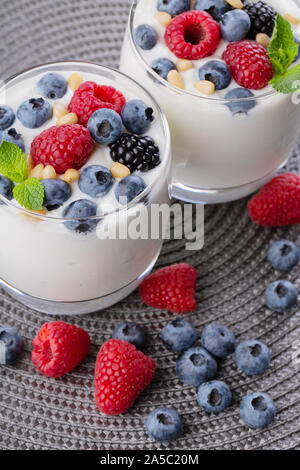 A glass of granola in yogurt with a mix of wild berries on a gray table. Top view, macro shot Stock Photo