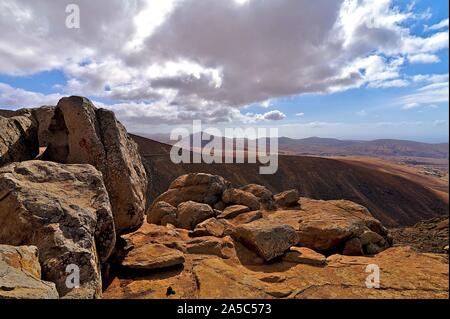 View on the dry soil of Fuerteventura with a passing road Stock Photo