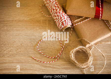Christmas details. Ribbons, ropes, gift boxes wrapped with craft paper, DIY and decor details. Wood background. Stock Photo
