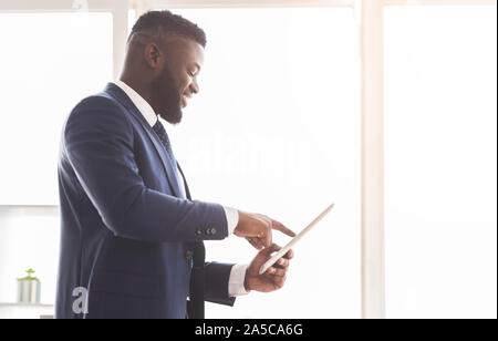 Young cheerful entrepreneur using digital tablet for business Stock Photo