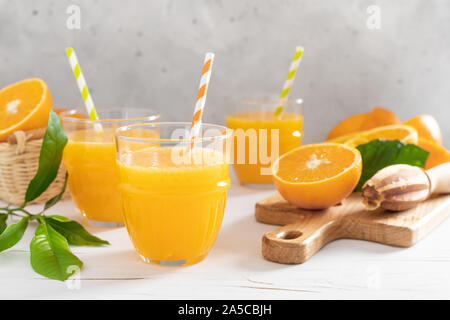 Orange juice. Freshly squeezed juice in glasses and fresh fruits with leaves Stock Photo