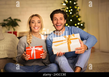 Millennial couple holding Christmas gift boxes and smiling Stock Photo