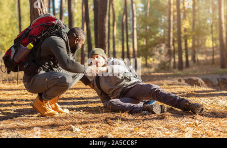 Black guy helping his injured friend to get up Stock Photo