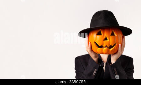 Man in black suit holding pumpkin head in hands on white Stock Photo