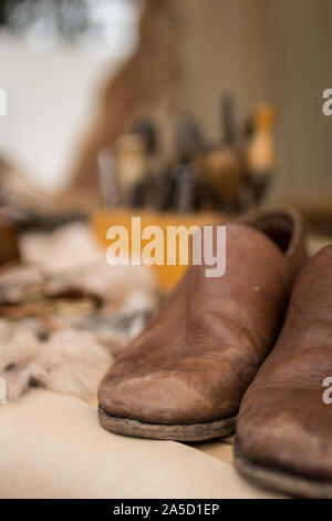 Ready shoes on shoemaker working desk and set of tools, material background, selective focus Stock Photo