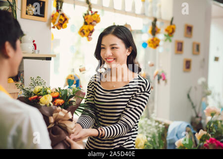Florist giving bouquet of flower to woman in flower shop Stock Photo