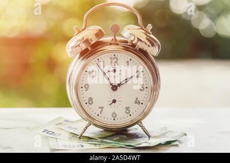 Old and rusty alarm clock and 100 hundredth euro banknotes. Business or time and money concept Stock Photo
