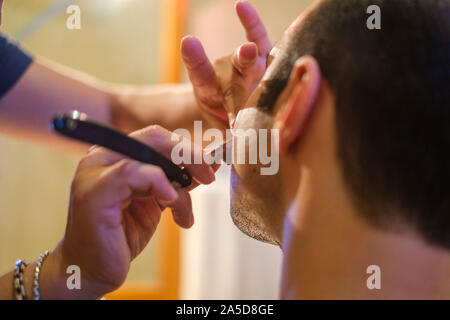 Close up photo of a barber shaving a client with a straight razor Stock Photo
