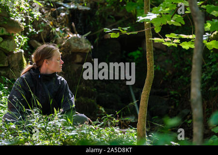 Woman sitting in the woods with eyes closed during a forest bathing session Stock Photo