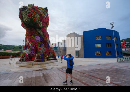 Man photographing the giant flower covered dog sculpture 'Puppy' by artist Jeff Koons in front of the Guggenheim Museum in Bilbao, Spain, Europe Stock Photo
