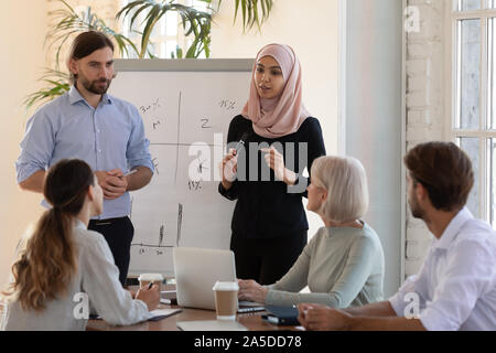 Two diverse business speakers give whiteboard presentation at conference training Stock Photo
