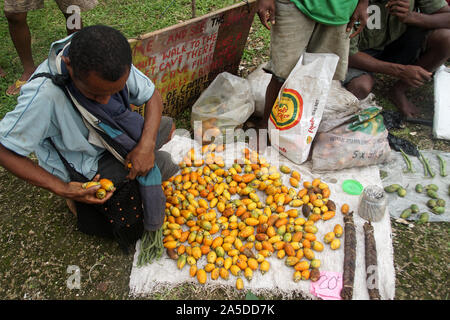Man buying ripe orange Betel Nuts from a Market Stall on Kiriwina Island Stock Photo