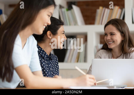 Different ethnicity students girls sitting at desk studying together Stock Photo