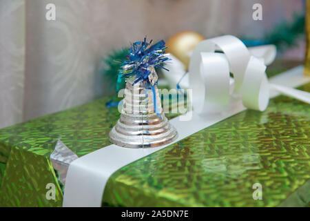 Christmas silver colored bells with Christmas Trimmings decorated. On top of the gift Stock Photo