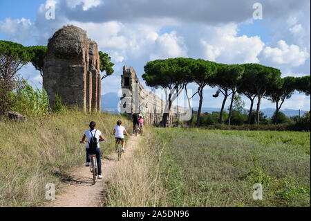 Rome. Italy. Parco degli Acquedotti, cyclists pass the ancient Roman aqueduct Aqua Claudia, begun by Emperor Caligula in 38 AD and finished by Emperor Stock Photo