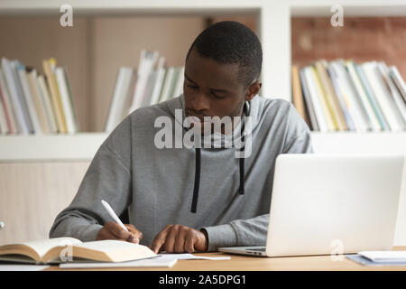 American fellow do schoolwork sitting at classroom table Stock Photo