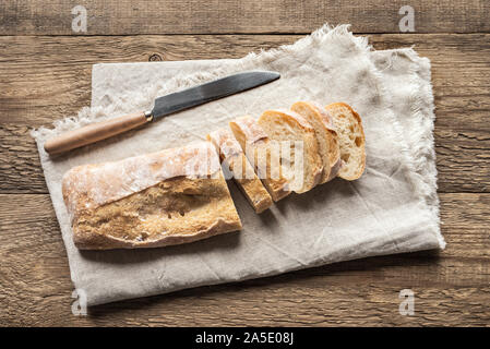 Ciabatta - Fresh Homemade Italian Bread sliced on napkin, wooden table, top view. Stock Photo