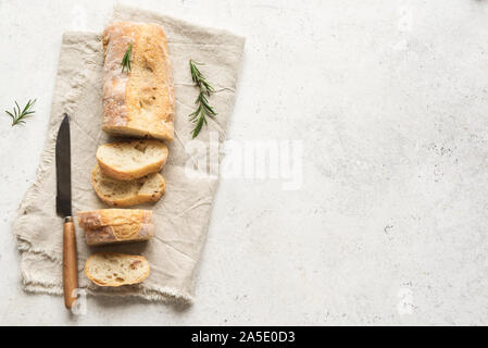 Ciabatta - Fresh Homemade Italian Bread sliced on napkin on white table, top view, copy space. Stock Photo