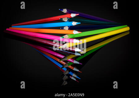 Colored upright crayons of different colors reflected on a black background Stock Photo
