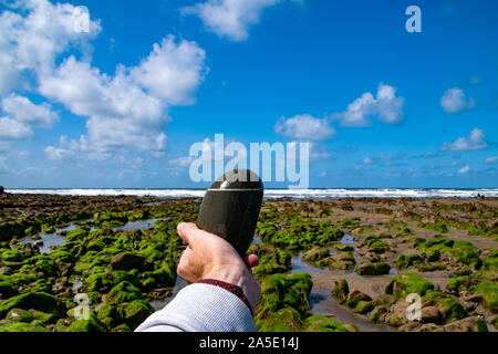 Abstract coastal scene of a hand holding a stone against the horizon. Photo taken at Boscastle in Cornwall, UK Stock Photo