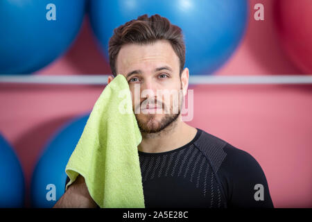 Portrait of a fit tired man wiping his face with a towel in the gym during training Stock Photo