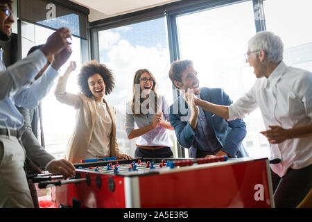 Employees playing table soccer indoor game in the office during break time Stock Photo