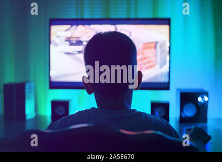 Boy as anonymous, using a computer or playing a game. View from back. Stock Photo