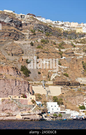 View from a boat to the crater wall of Santorini, Greece with the center of the capital Fira up on the crater rim. To the left is the famous cable car Stock Photo