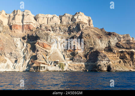 View from a boat to the southeastern crater wall of Santorini, Greece with some old industrial buildings for pumice export down at the coast. Stock Photo