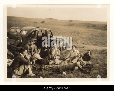 Early 1900's photograph of group of friends having a picnic beside a vintage car, in moorland countryside, circa mid 1930's, Ayrshire, Scotland, U.K. Stock Photo