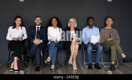 Smiling multiethnic professionals sit on chairs looking at camera Stock Photo
